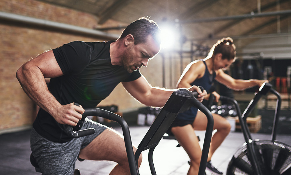 Man and woman using exercise equipment at a gym